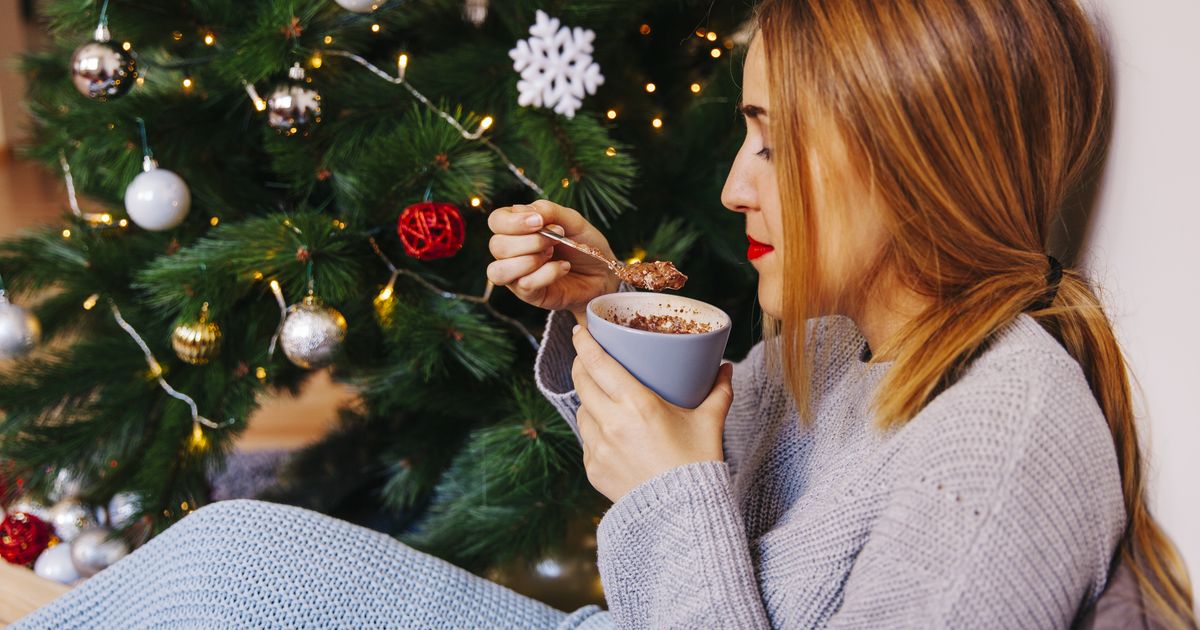 Karácsonyfa mellett ülő nő lassan, tudatosan eszik és mélyeket lélegzik