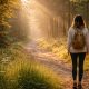 Nő áll az erdő szélén reggeli fényben, mielőtt elindul az ösvényen - a belső folyamat kezdetének hangulata